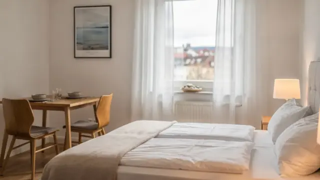 Moderne Ferienwohnung in Konstanz mit Bett, Esstisch und hellem Fenster im Thema Ferienwohnung Konstanz.