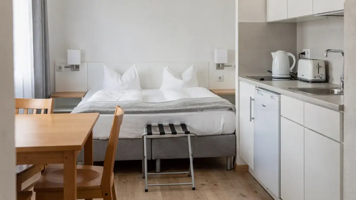 Moderne Ferienwohnung am Bodensee mit Bett, Küchenzeile und Esstisch als typische Ausstattung