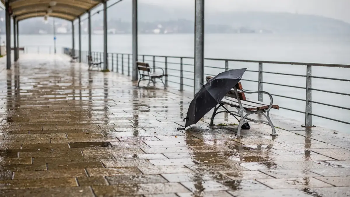 Regnerische Uferpromenade am Bodensee mit Schirmen und nassem Pflaster als Thema für Bodensee-Regen-Aktivitäten